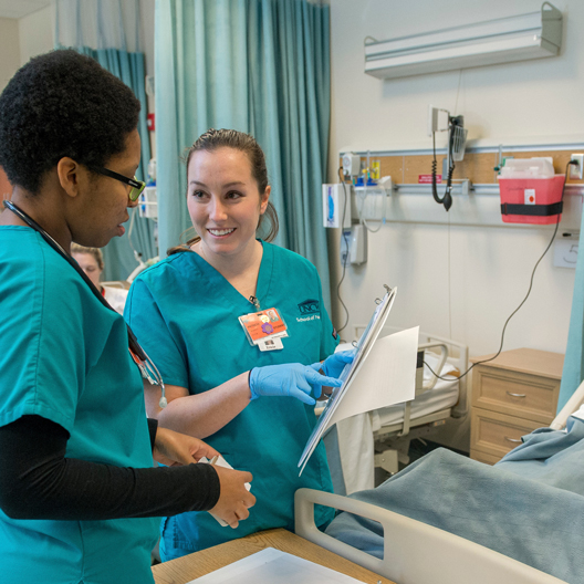 Two students examine a chart next to a manikin