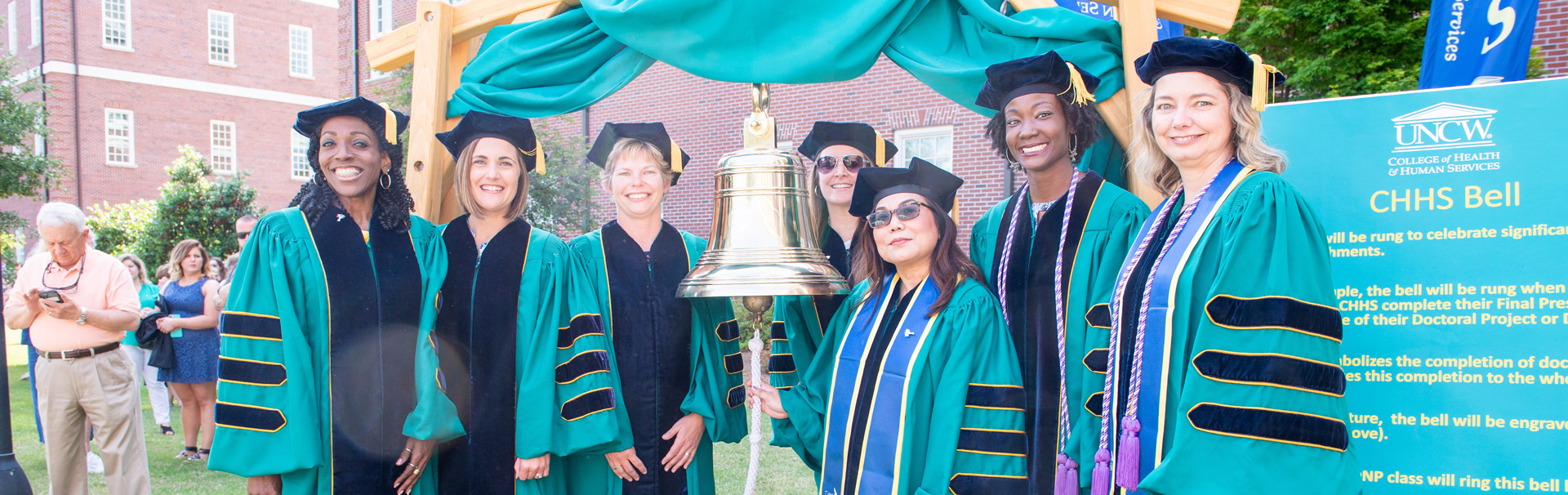  The inaugural class of UNCW’s Doctor of Nursing Program on the McNeill Hall lawn next to the ceremonial bell that is rung for commencement