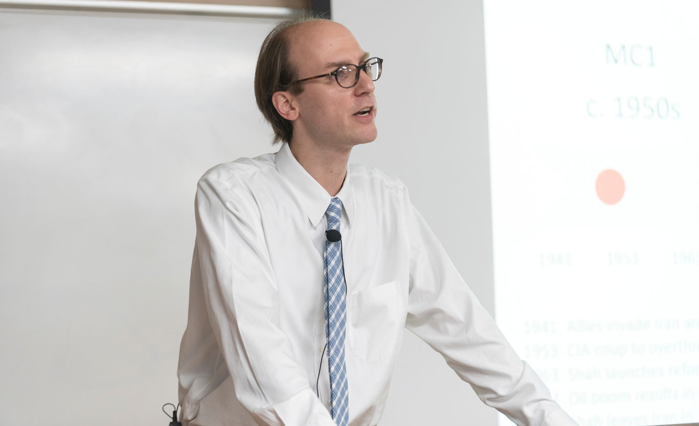 Assistant Professor giving lecture with projector in background