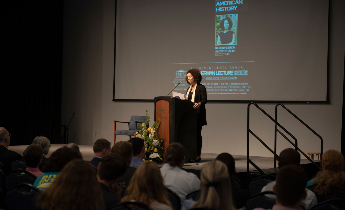 Speaker giving lecture with projection screen in the background