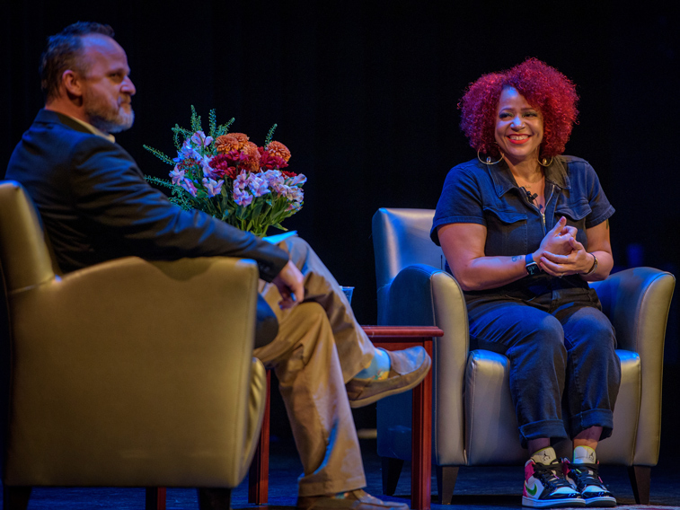 Two presenters sitting in chairs talking on stage