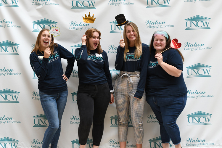 Four Watson students posing with props for photo