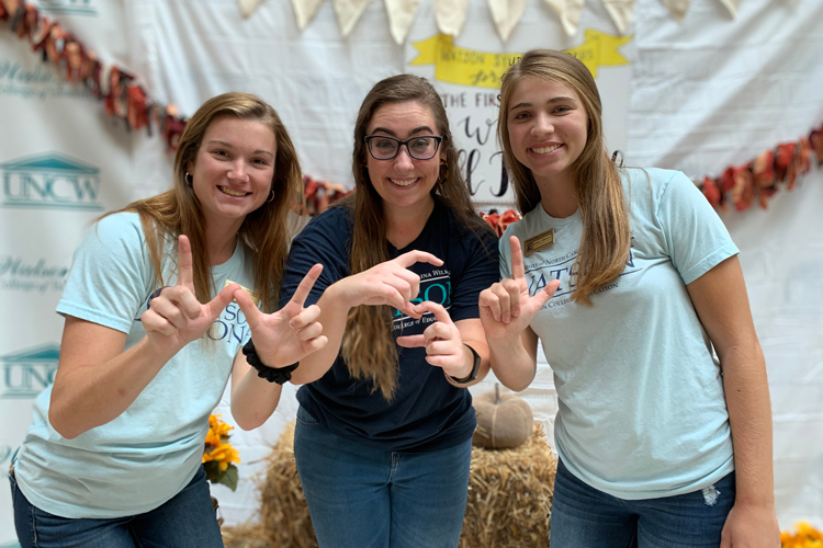 Three people holding up WSL with their hands
