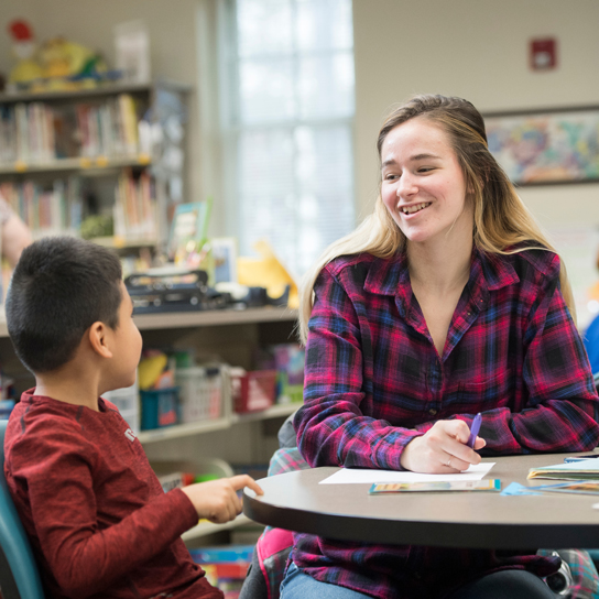 Student talks at table with youth