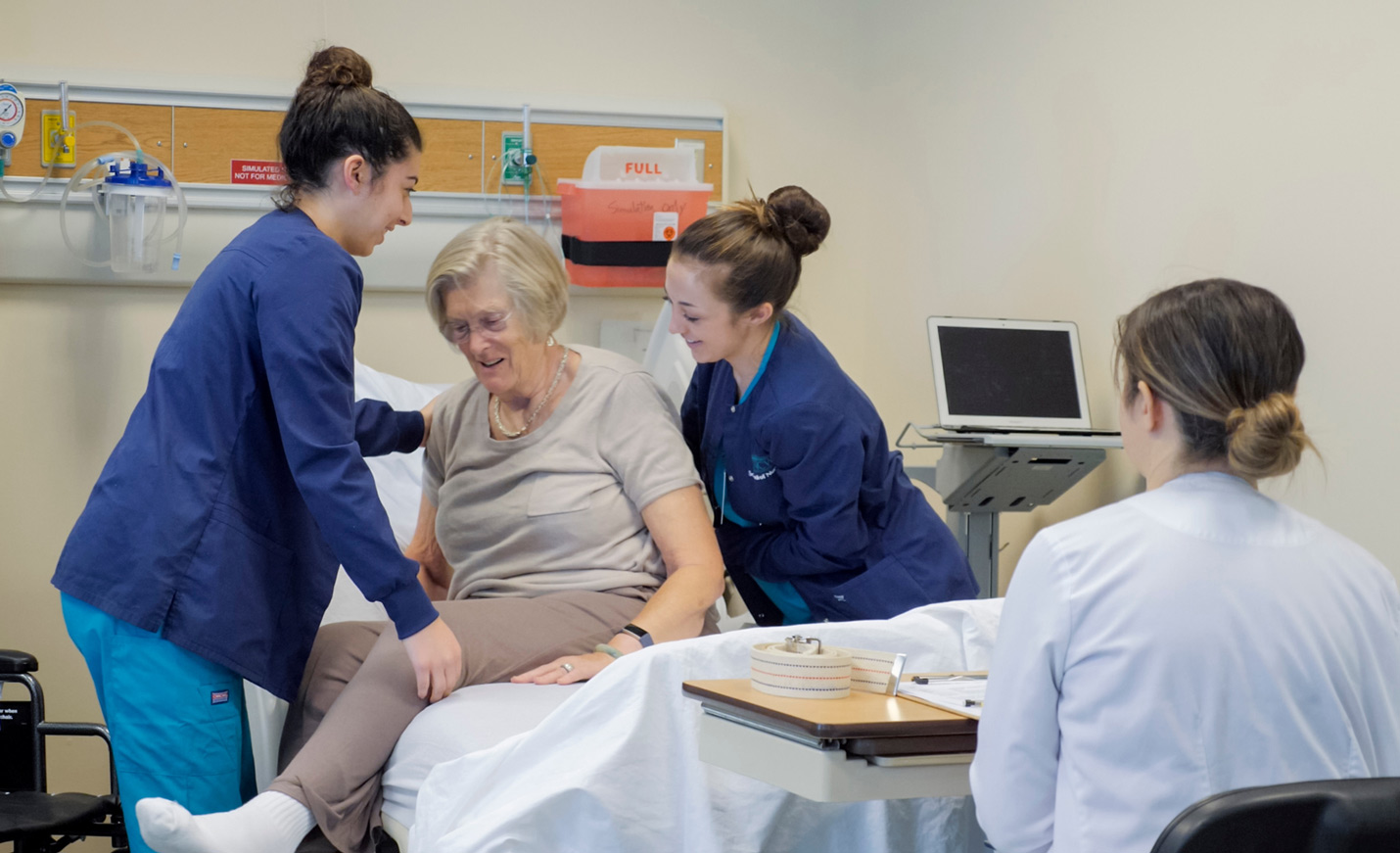Two nursing students assist an older adult patient out of a hospital bed.