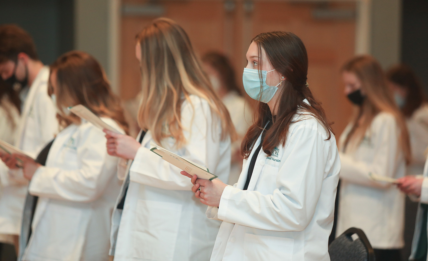 Nursing students stand in white coats for their white coat ceremony.