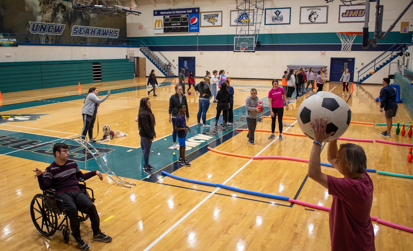Several participants of the School of Health and Applied Human Sciences I Can Do It, a physical-activity programs for individuals with disabilities, both physical and cognitive, in the Wilmington community, play with inflatable soccer balls and use basketballs for bowling in the Student Recreation Center gym.