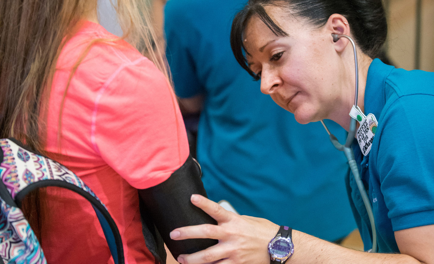 A woman takes the blood pressure of a young girl.