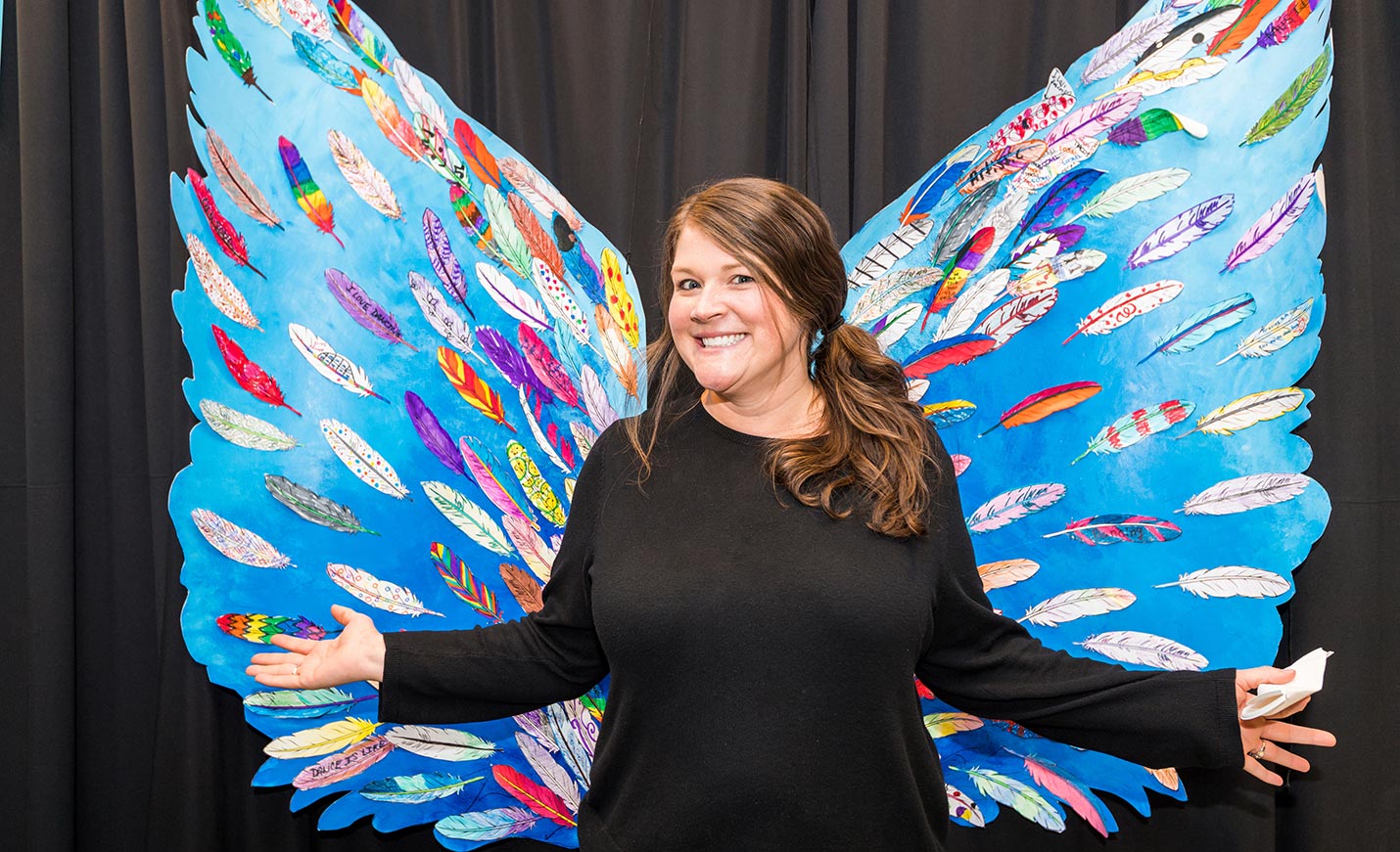 Kristin Mapson wearing wings in front of an art installation.