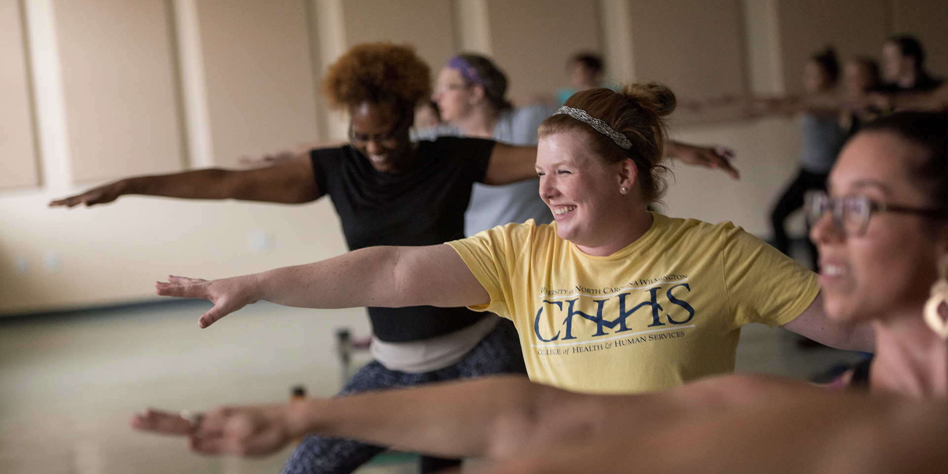  A yoga class makes a pose, with a person in a CHHS shirt in focus