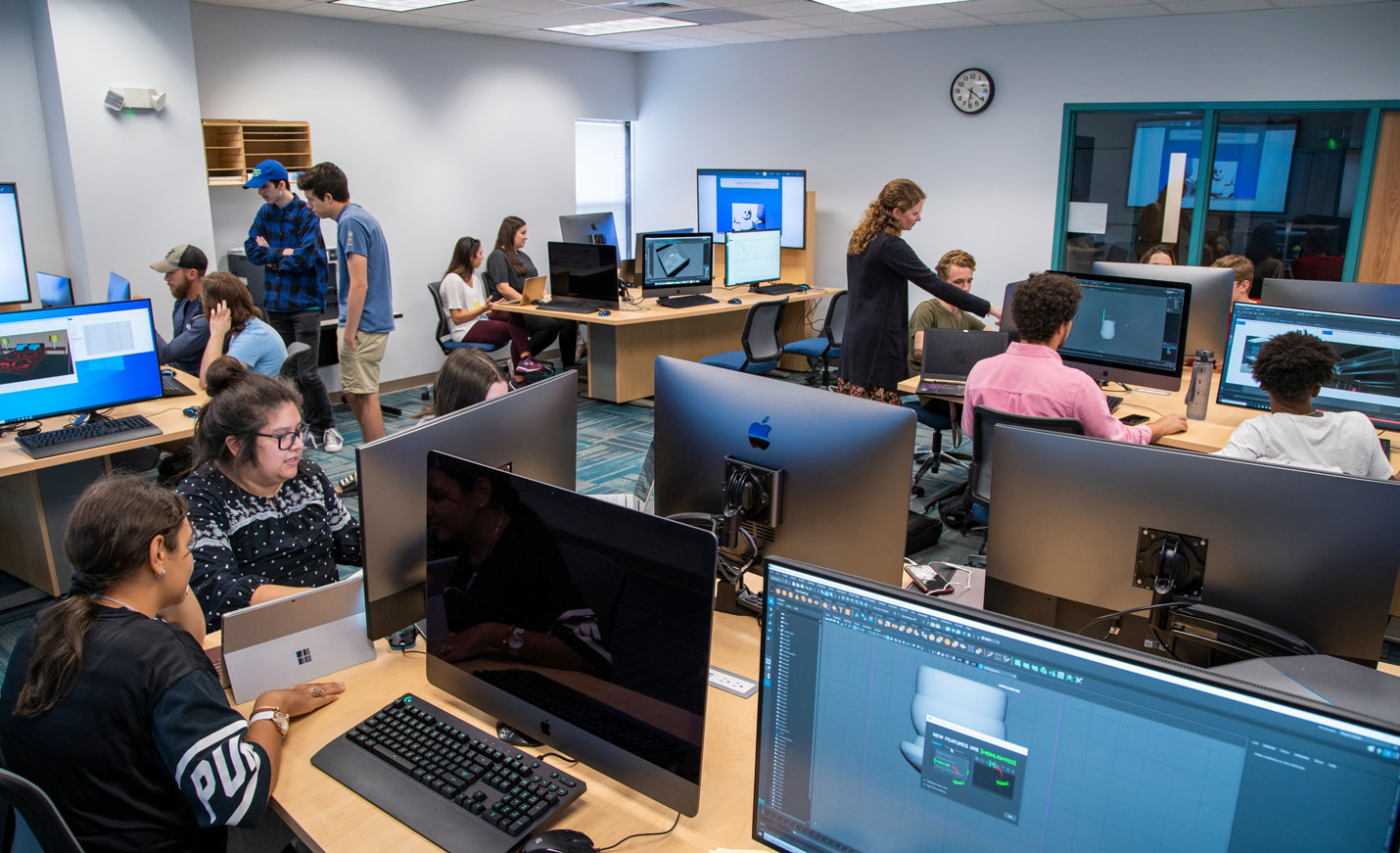 An instructor and a class full of students in the Digital Arts lab