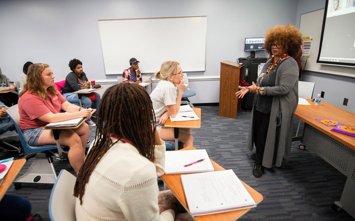An instructor stands at the front of a classroom full of students