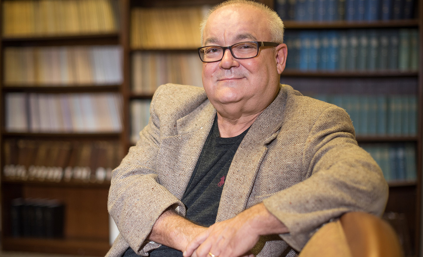 A faculty member sitting in front of shelves of books