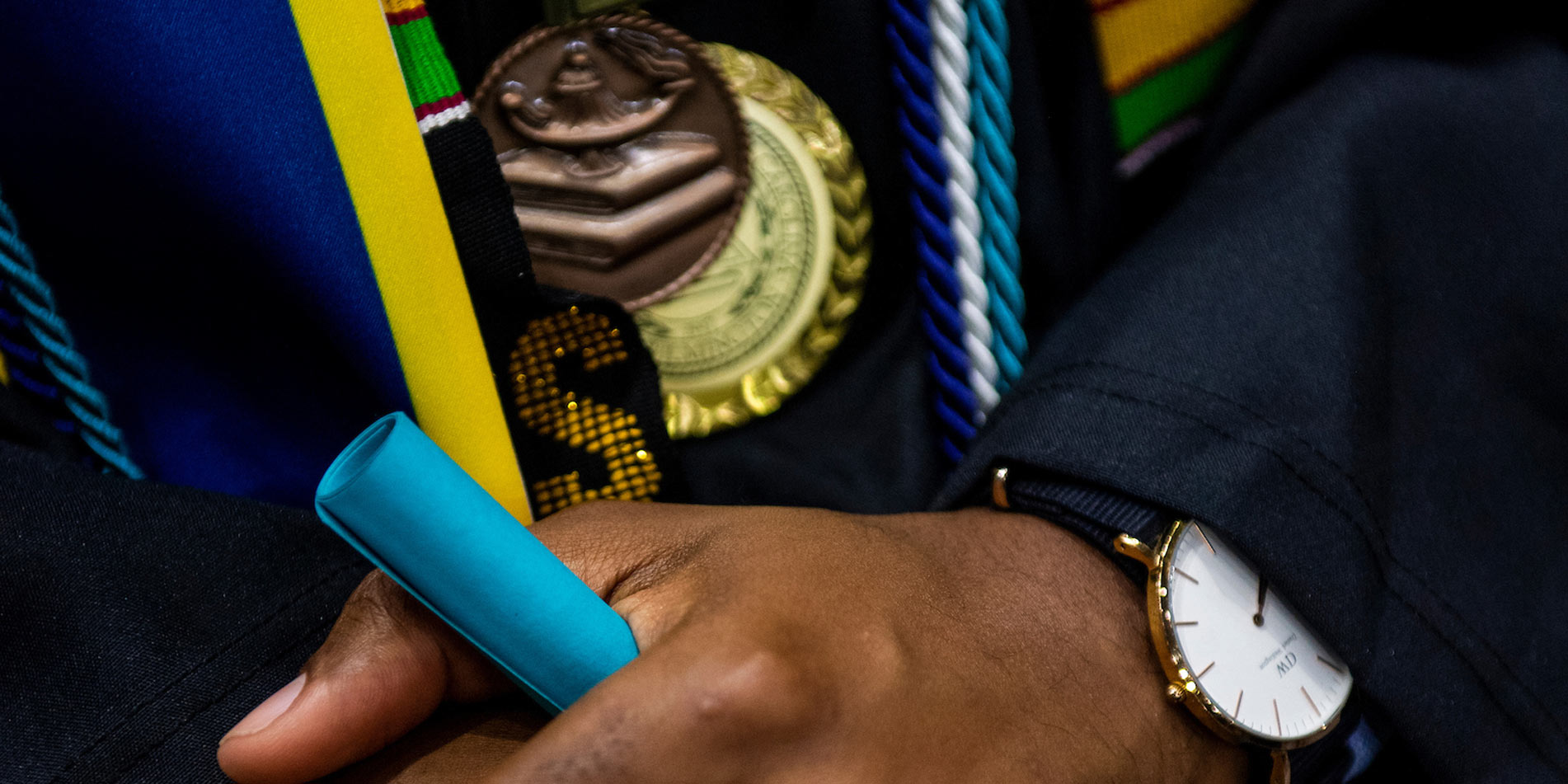 Graduate hands with rolled teal paper