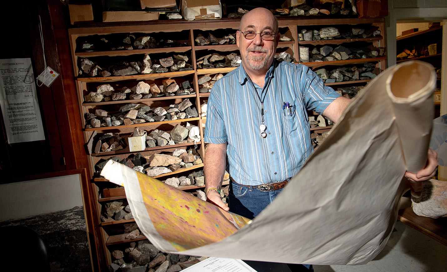 faculty member holding a cloth map on scrolls.