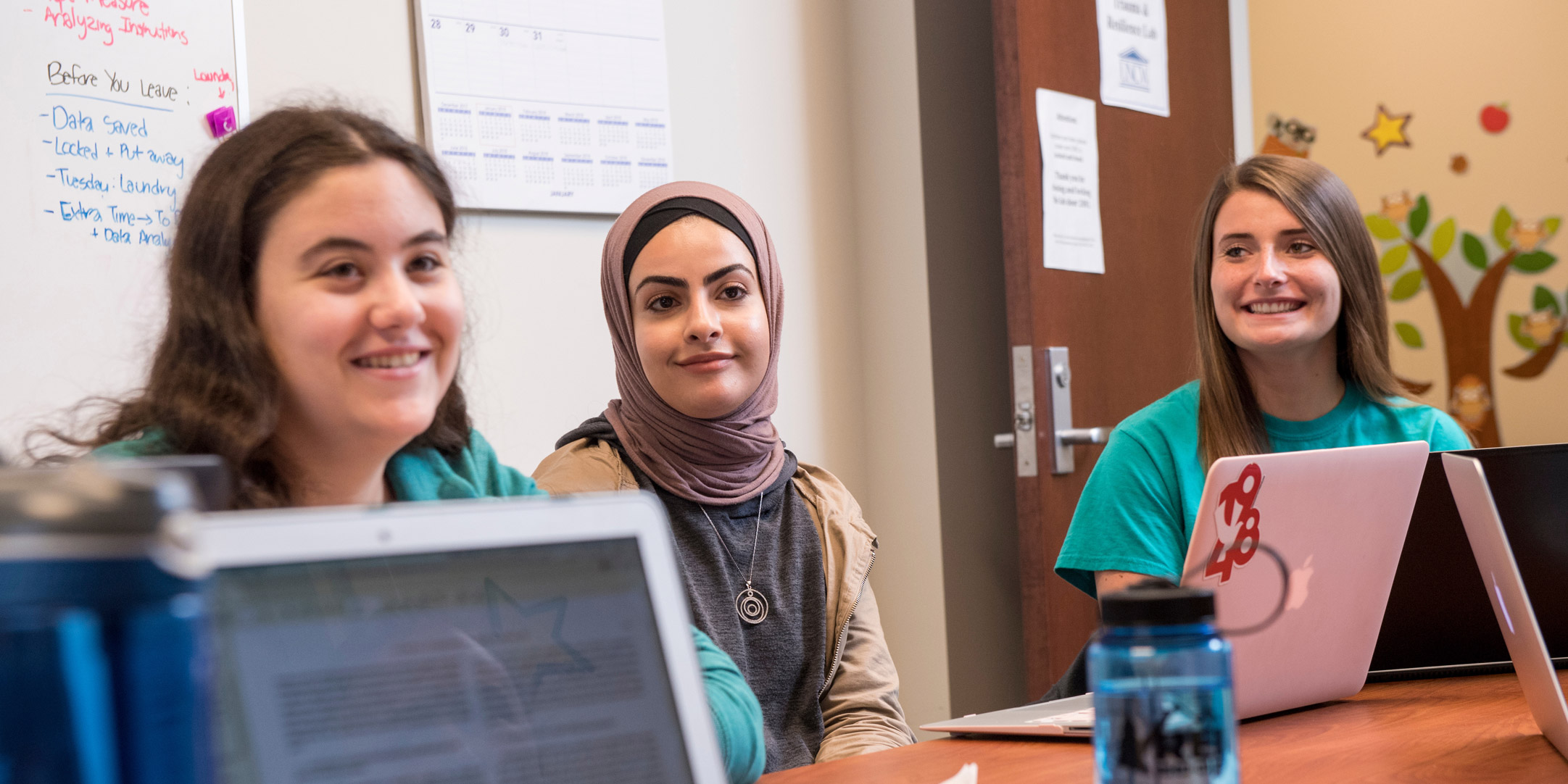 Three students smiling during a class