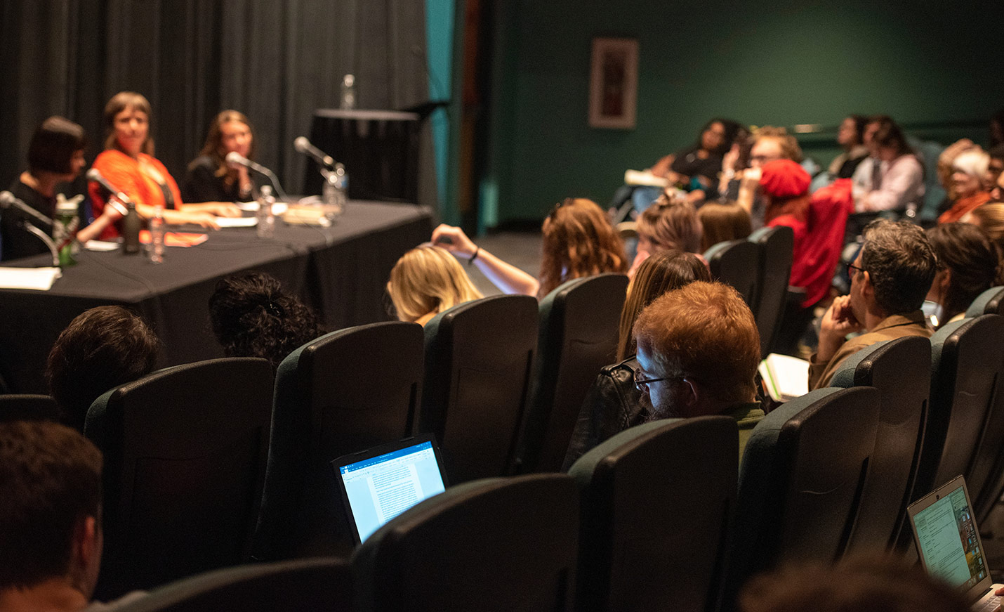 students in an auditorium listening to a panel discussion