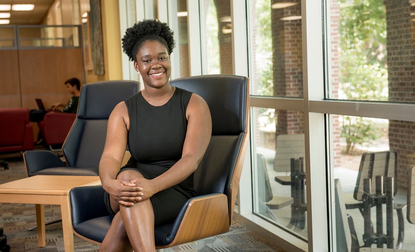 Former SGA President Ottille Mensah sitting in a chair near the window in a student lounge
