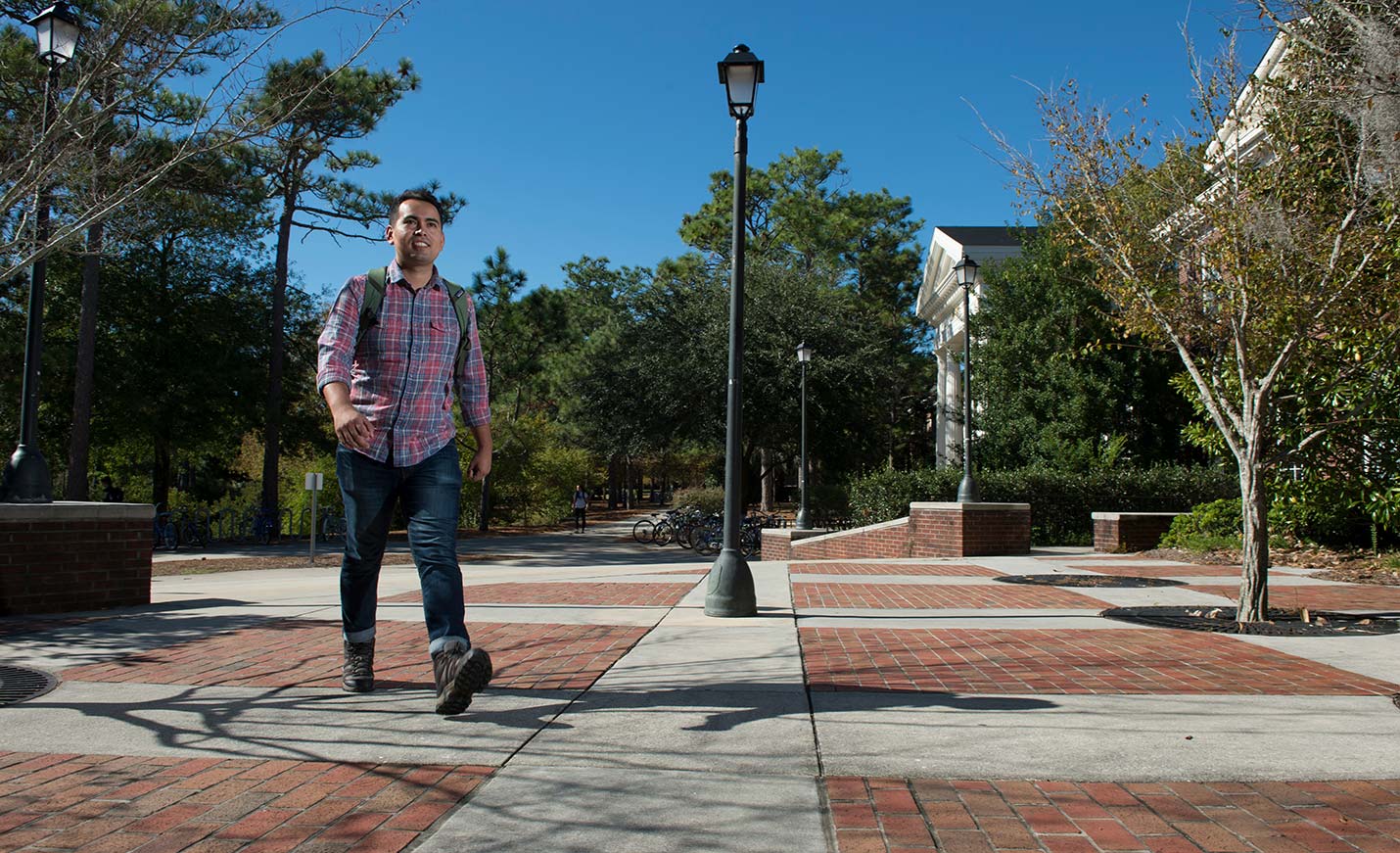 A student walking on Chancellor's Walk near a streetlamp