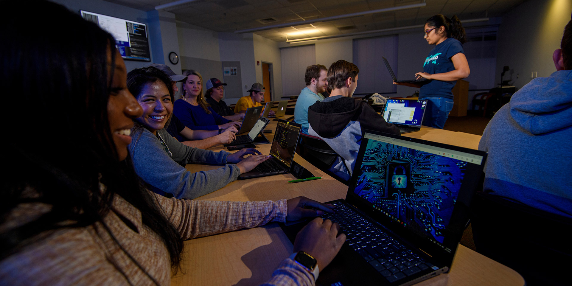 A group of students using laptops, with the student in foreground’s laptop displaying a screen with a lock on it