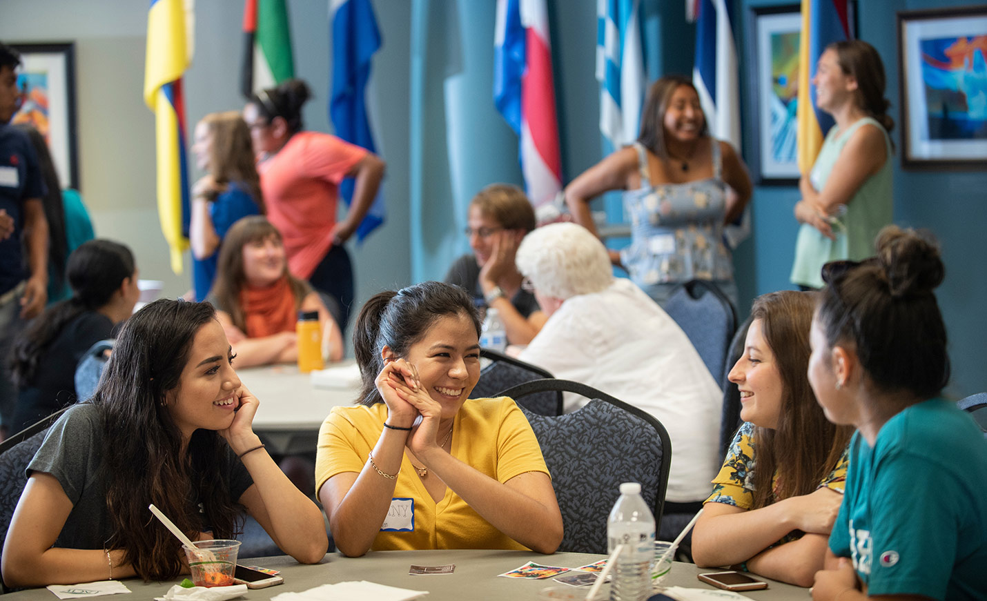 Four students sitting at a table, talking and smiling