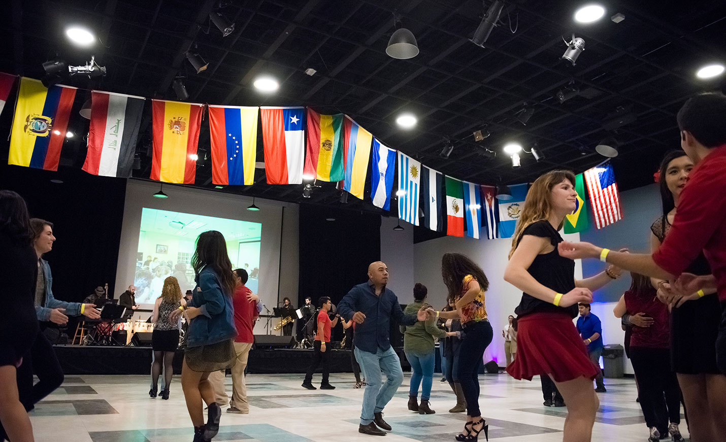 A group of people dancing in front of a large screen