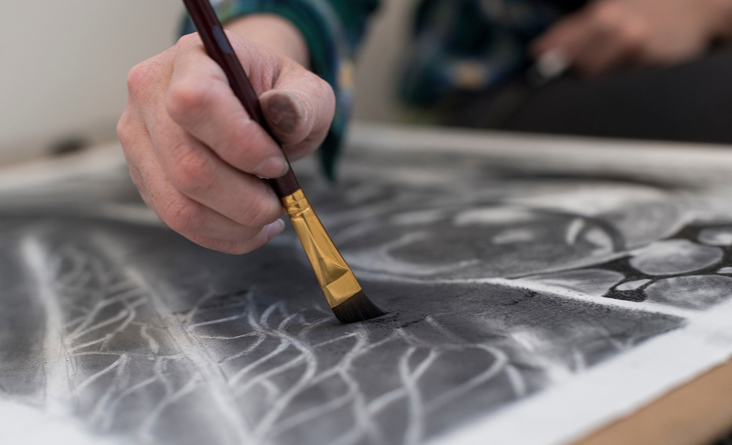 A close-up of a hand using a paintbrush on paper