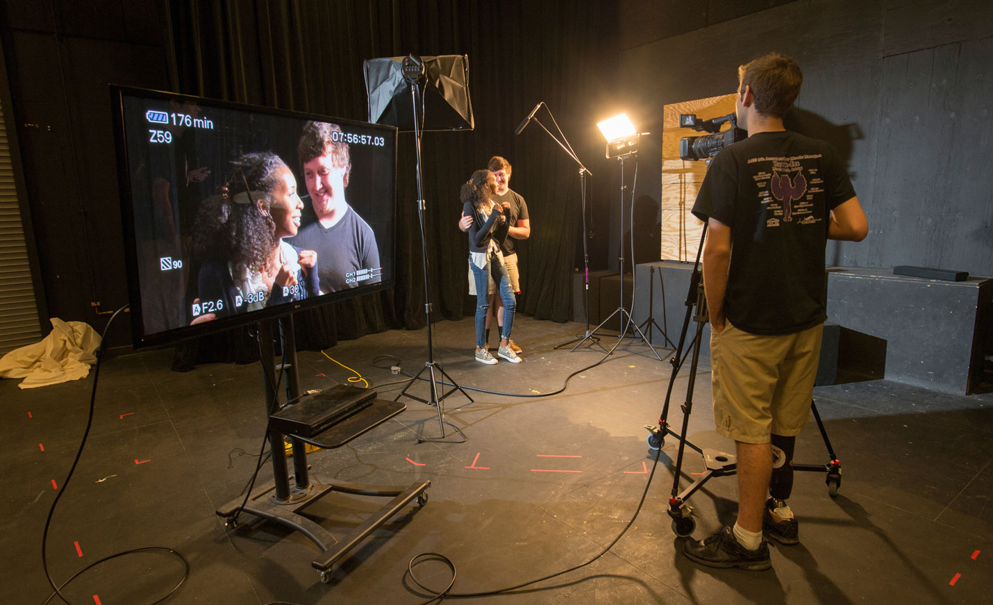 Students posing for the camera; their image is projected on a large screen