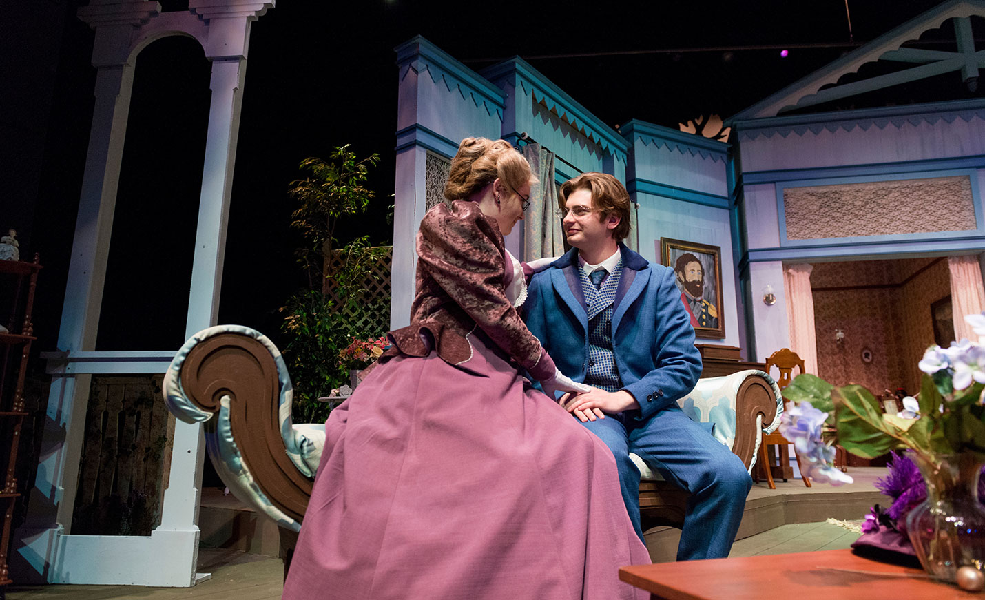 Two actors in period dress on a settee