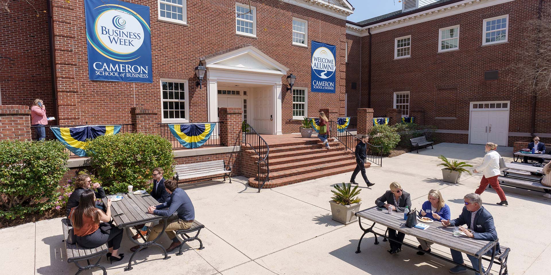 People sit on various picnic benches outside during Business Week