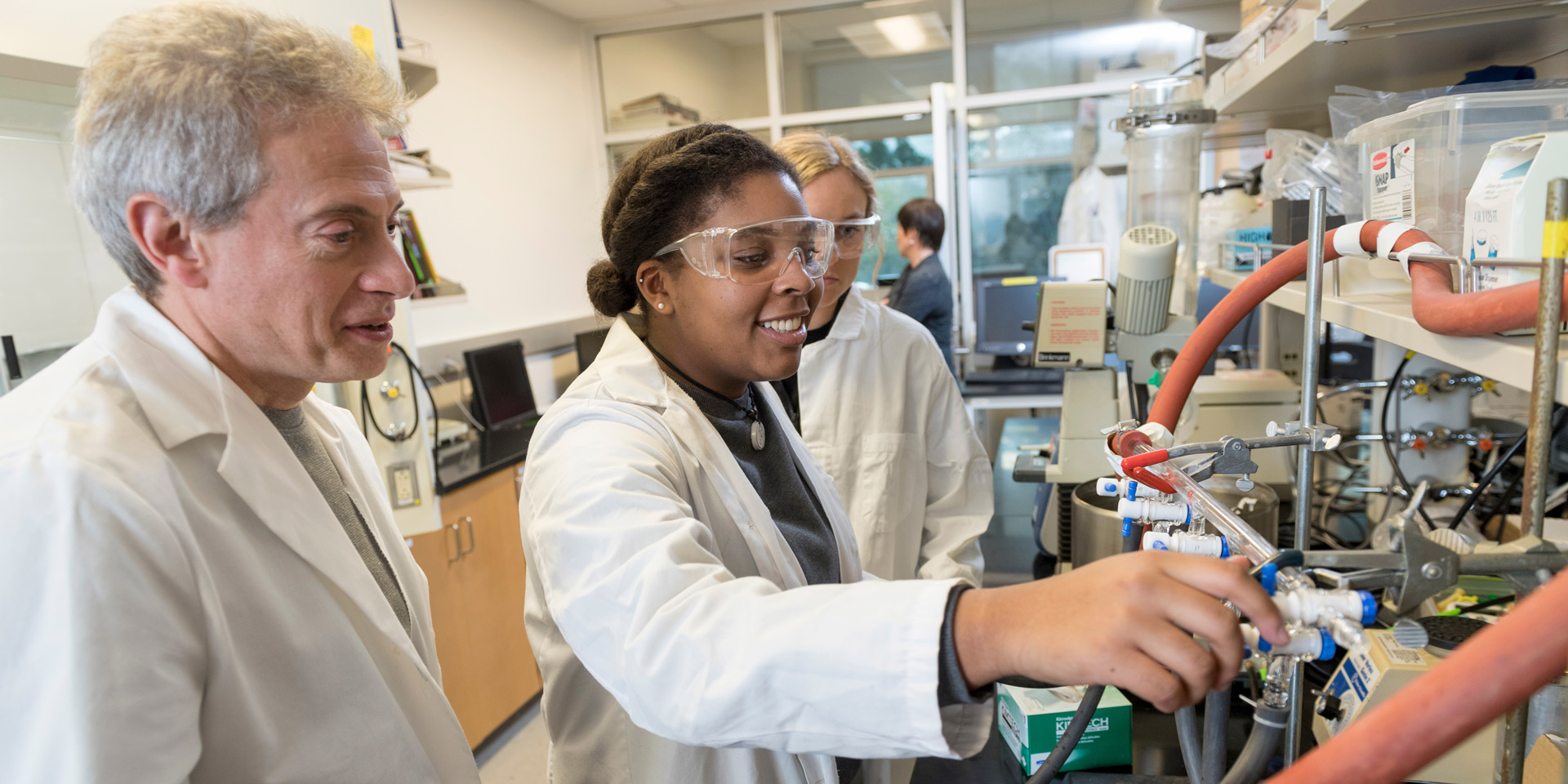 A professor and two students work on equipment in a lab