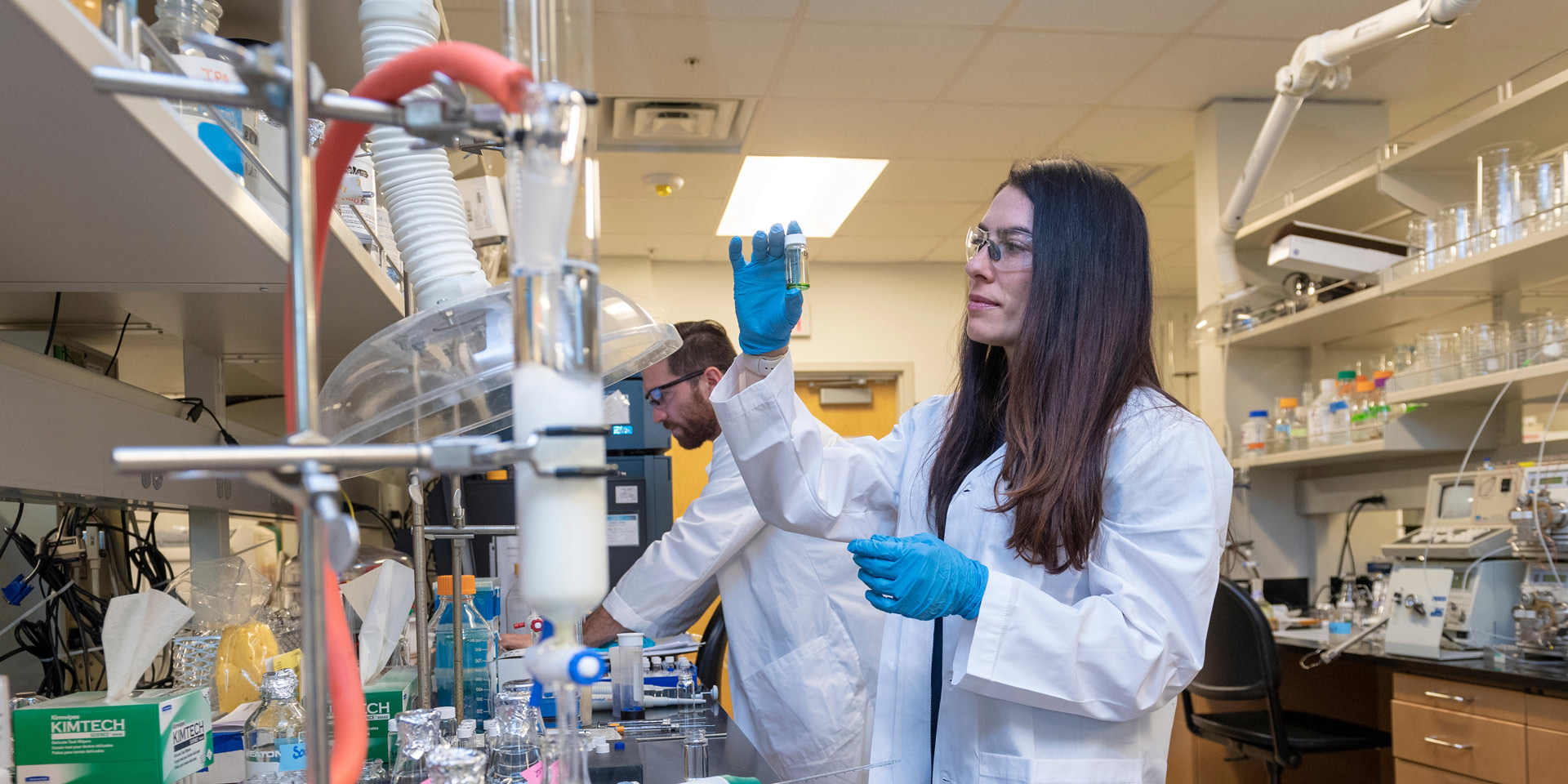 A student examines a beaker while performing an experiment