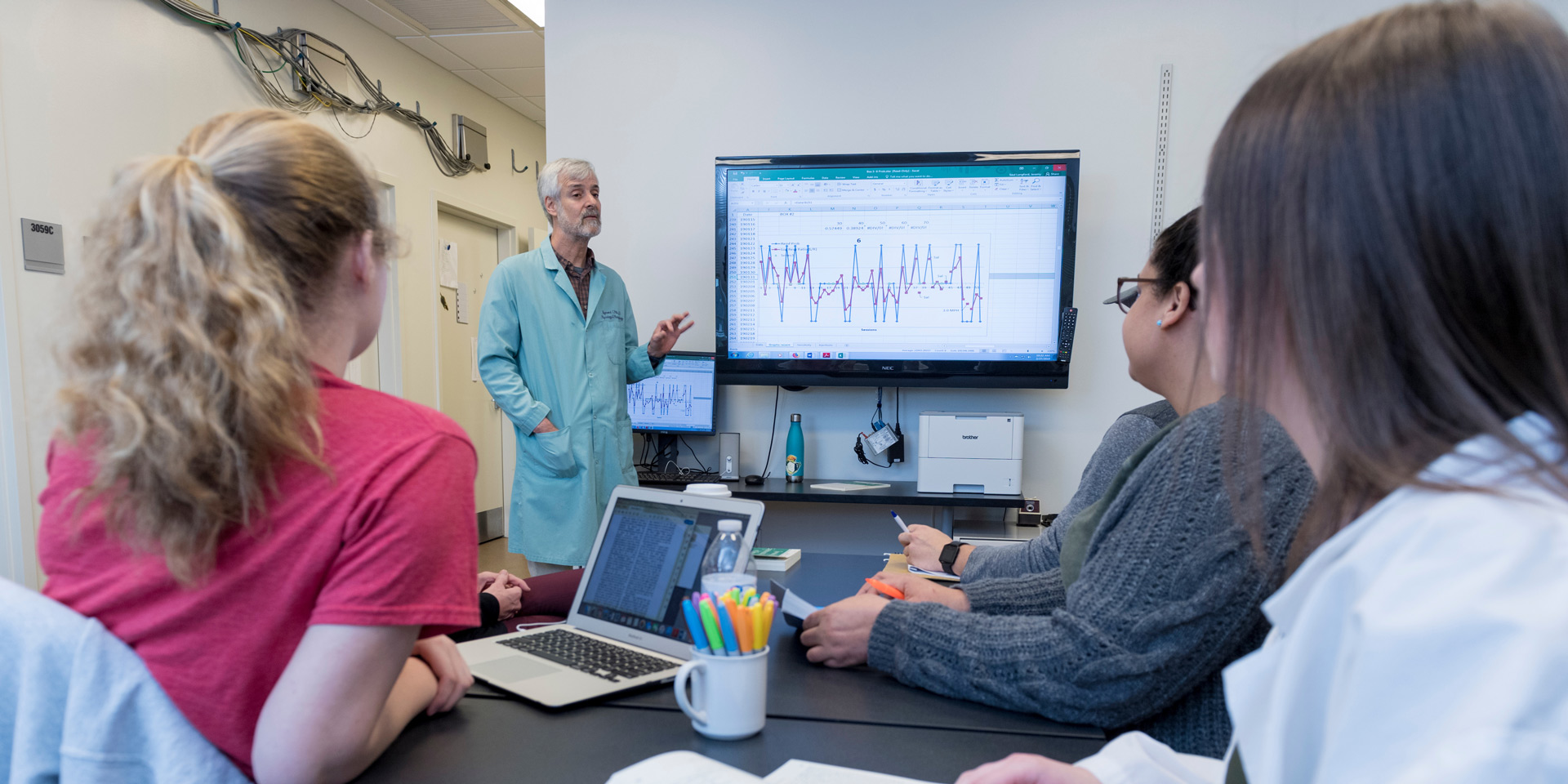 A professor discusses data with a group of students