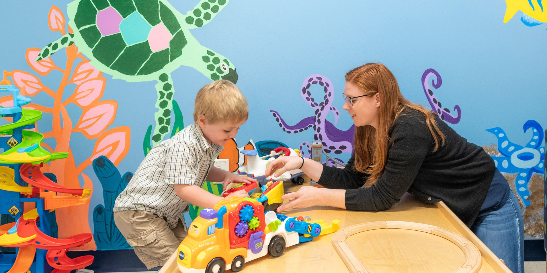 Psychology student plays with child with children's toys on a table