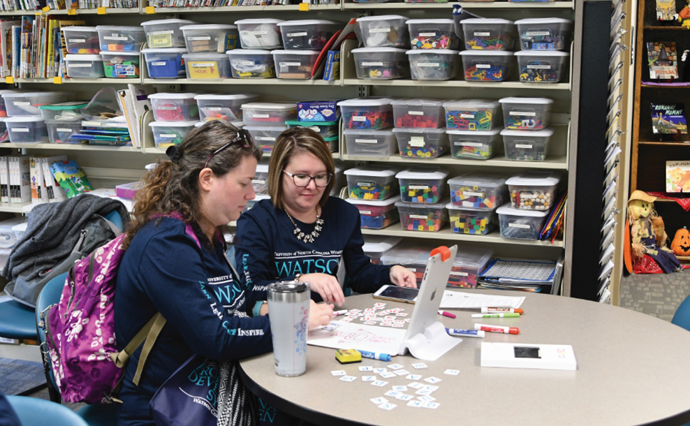 Two Watson students sitting at a table with an ipad