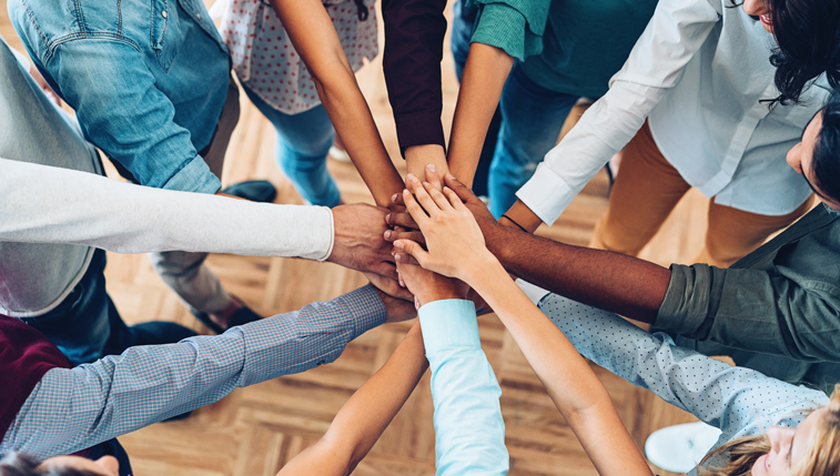 A diverse group of people putting their hands together in a circle