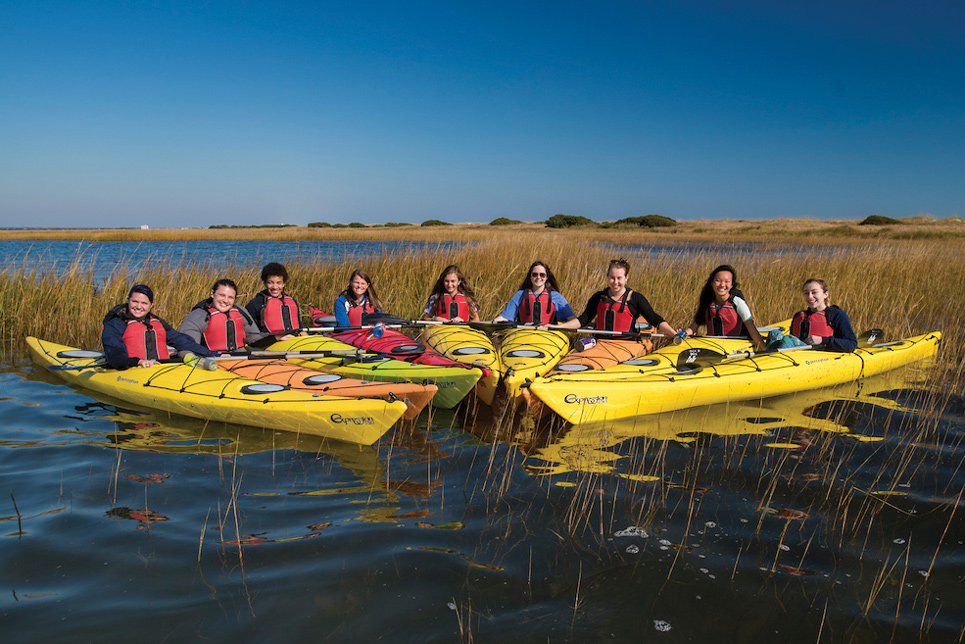 Nine students in kayakys posing for a photo