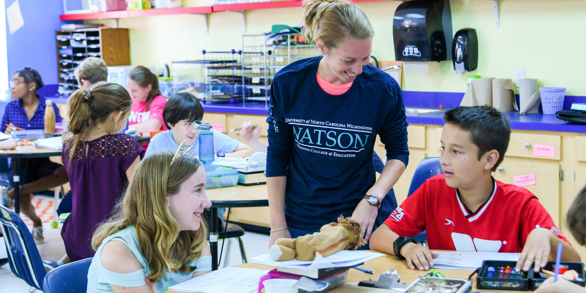 Student helps childen in classroom.
