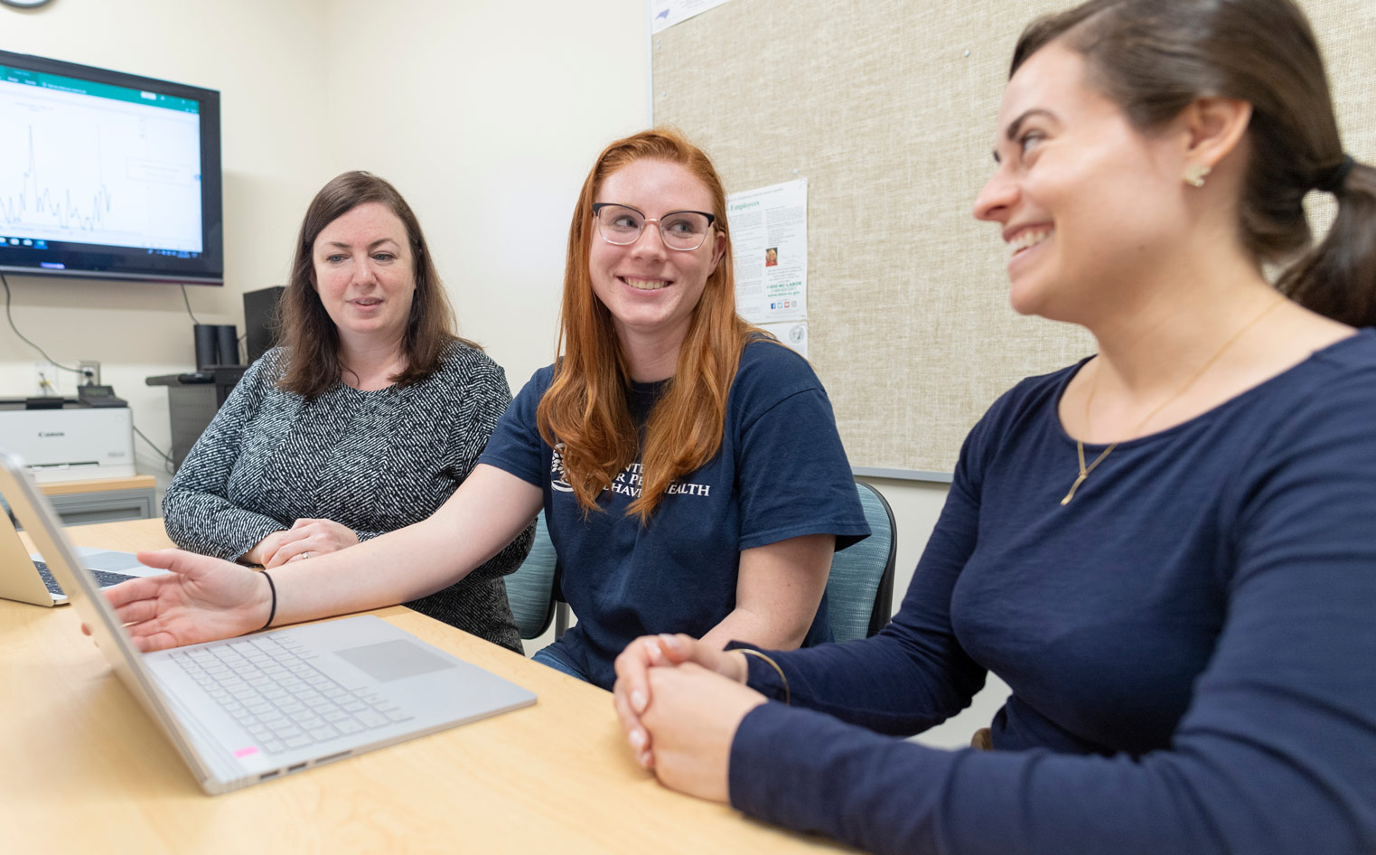 three members of the seahawk community have a discussion around a laptop