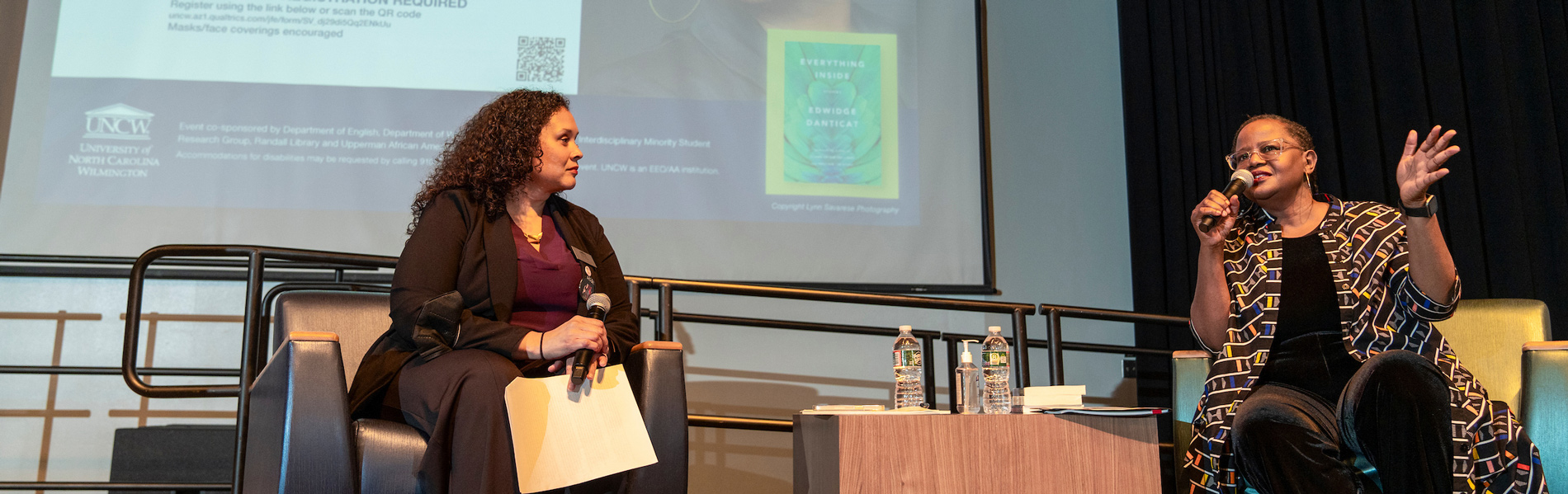 Two women speaking on stage at a lecture
