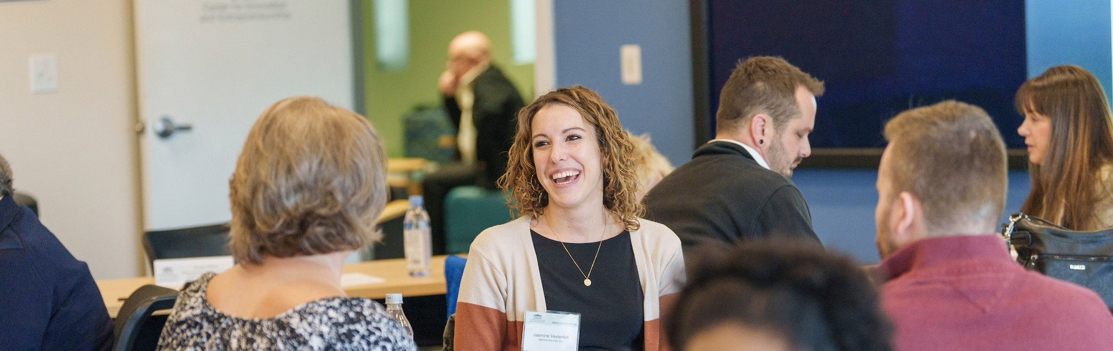 Entrepreneur smiling as she receives mentoring from two mentors sitting across from her.