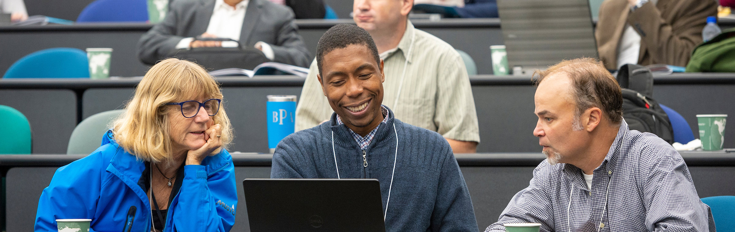 Three professors sharing a laptop