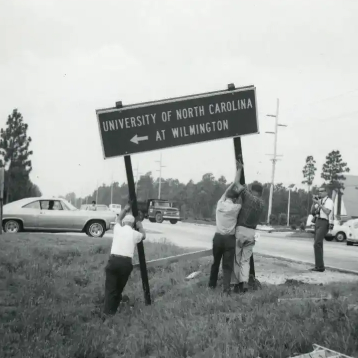 Crews installing a road sign for the recently renamed University of North Carolina Wilmington in 1969. Photo courtesy UNCW and the University Archives at UNCW Library 