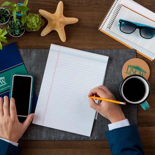 student writing and holding phone