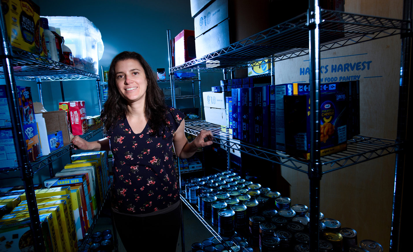 A woman standing among stocked shelves in the Hawks Harvest food pantry