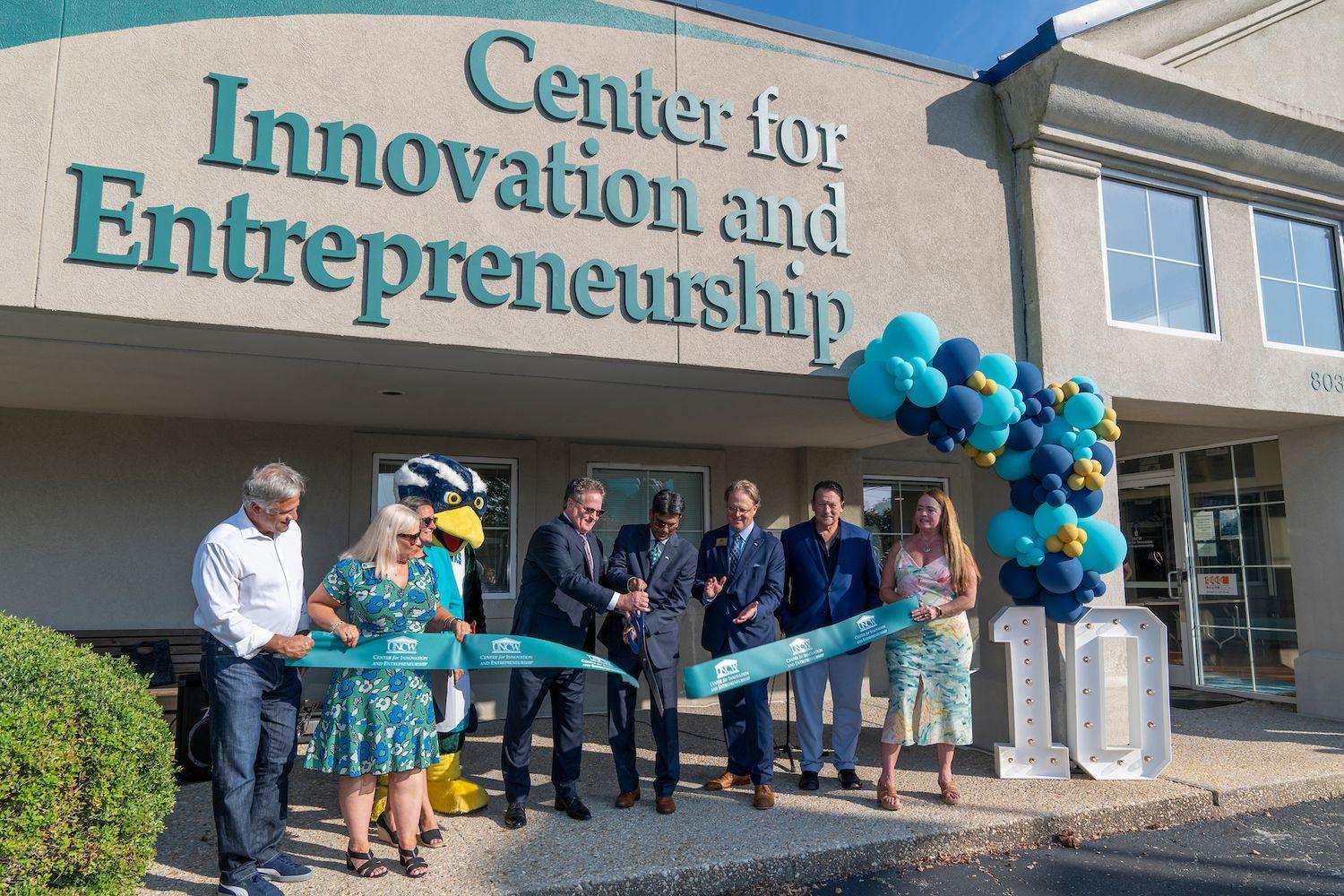 Chancellor Volety cuts a ribbon with a group that includes Sammy C. Hawk in front of the Center for Innovation and Entrepreneurship