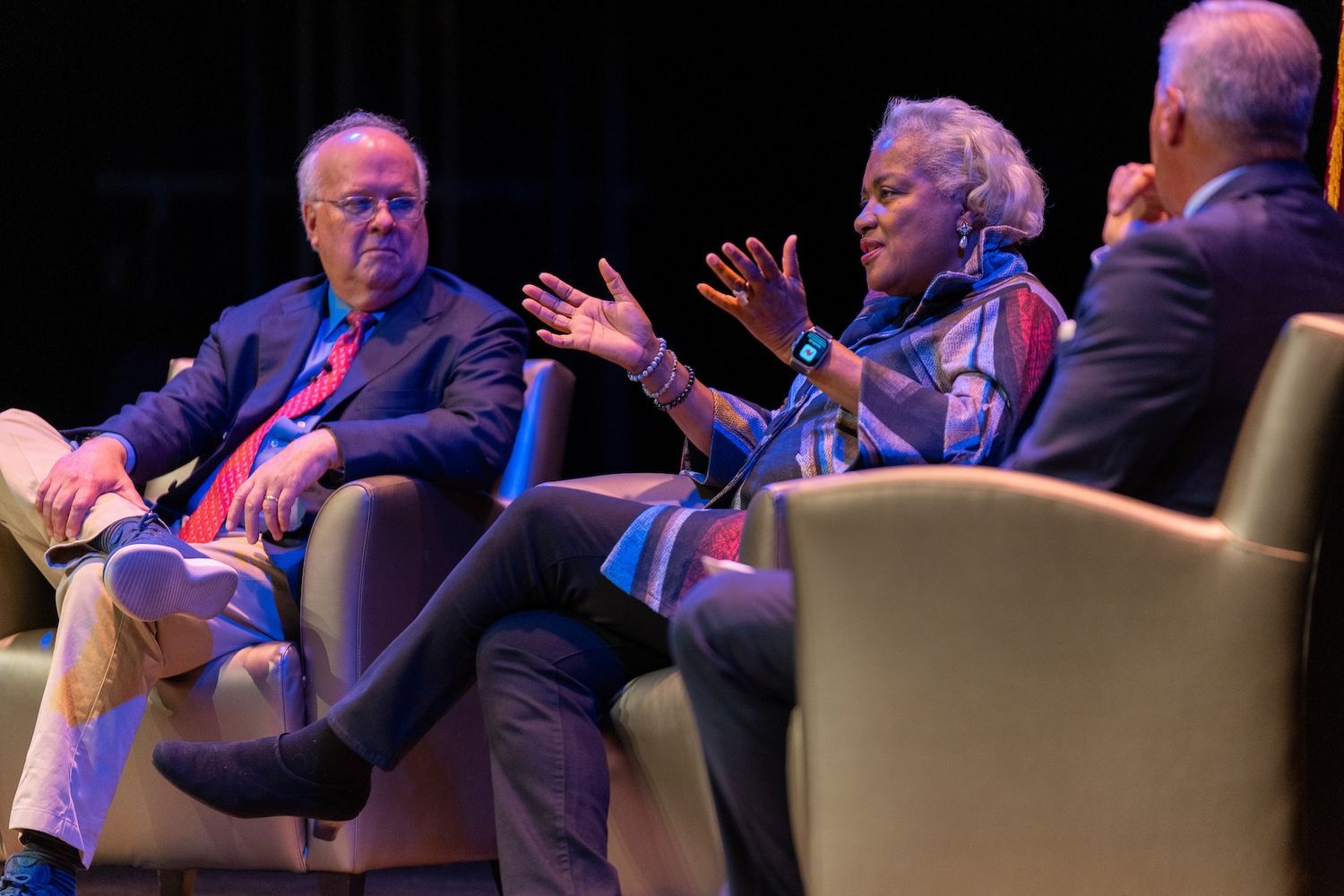 Karl Rove listens to Donna Brazile speak while both sit on stage