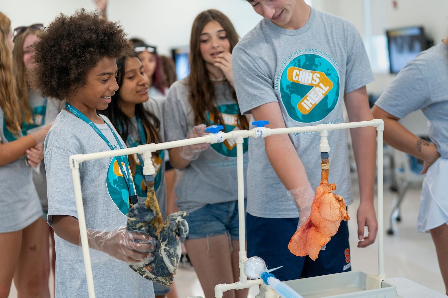 Two iHEAL summer campers  touch the pig lung models to learn about Respiratory Therapy.