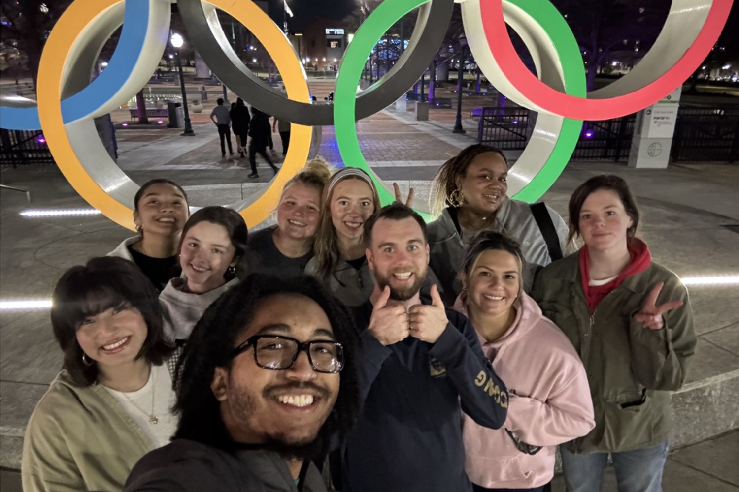 Immersive Service students taking a group selfie in front of the Olympics sign