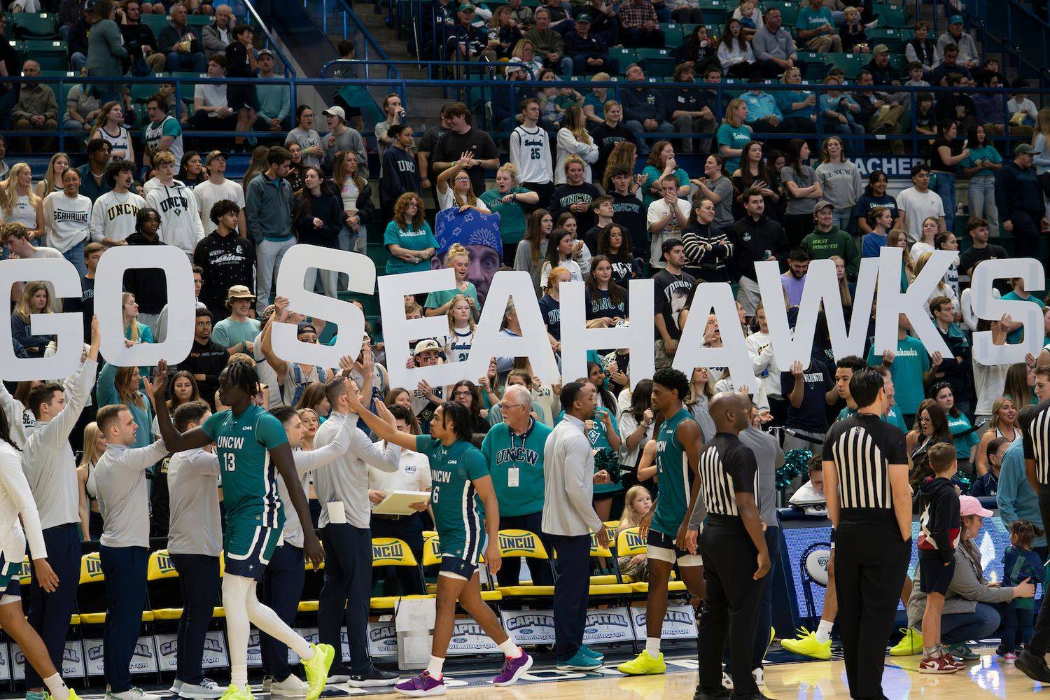 crowd at basketball game holds up letters reading GO SEAHAWKS